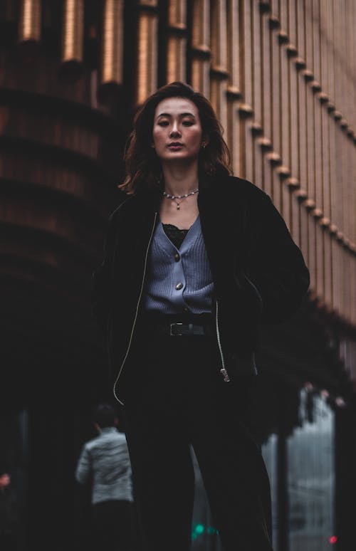 무료 갈색 나무 벽 근처에 서있는 검은 재킷에 여자 스톡 사진