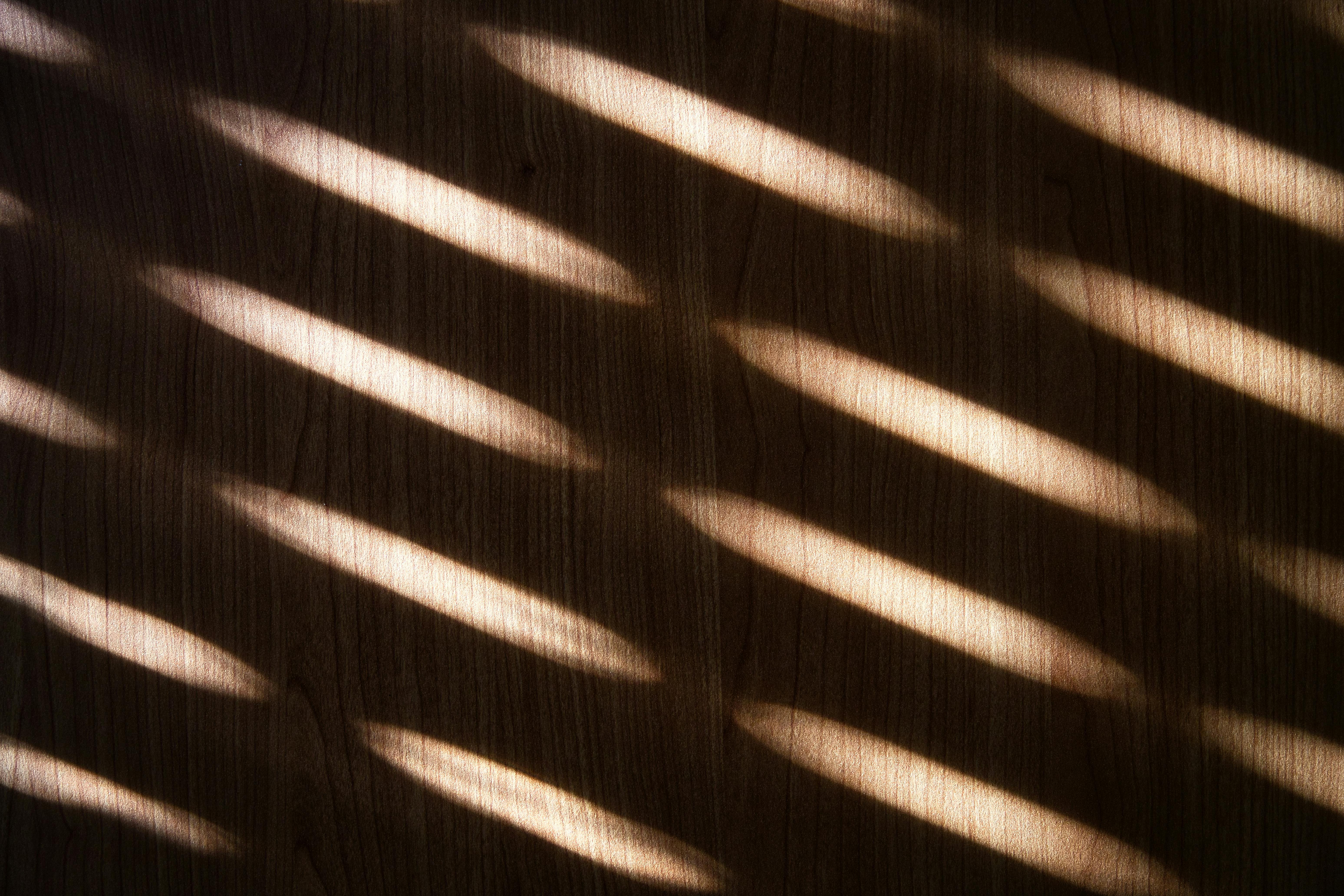 Gratis La luce del sole crea motivi astratti attraverso le persiane su una superficie di legno a Pforzheim, in Germania. Foto a disposizione