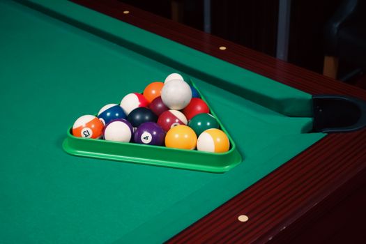 A set of colorful pool balls arranged in a triangle on a green billiard table, ready for a game.