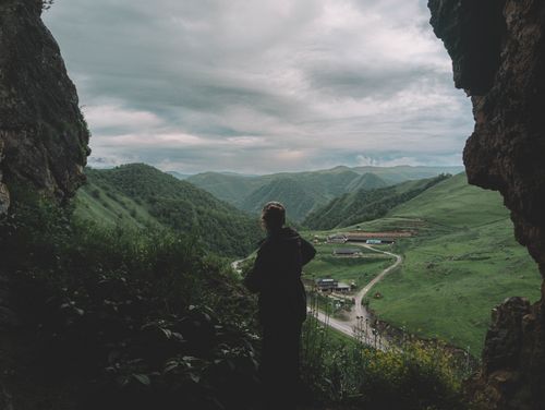 Free A silhouette of a person enjoying the rural landscape from a cave in Akhsau, Russia. Stock Photo