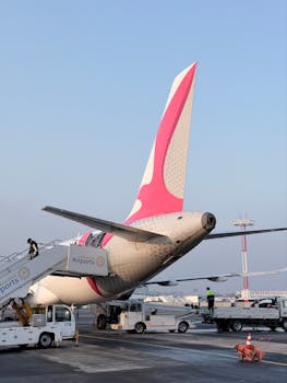 Aircraft on tarmac at Abu Dhabi airport with crew, bathed in morning light.