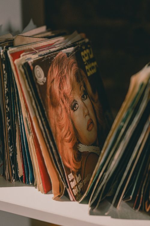 Free Stack of retro vinyl records with colorful covers on a shelf, showcasing a nostalgic vibe. Stock Photo