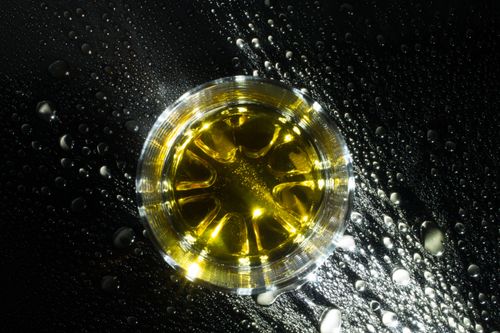 Free Artistic shot of whiskey in glass with ice on a wet, textured surface. Perfect for beverage stock images. Stock Photo