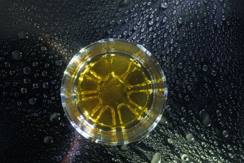 Free An artistic view of a glass with yellow liquid surrounded by water droplets on a dark surface. Stock Photo