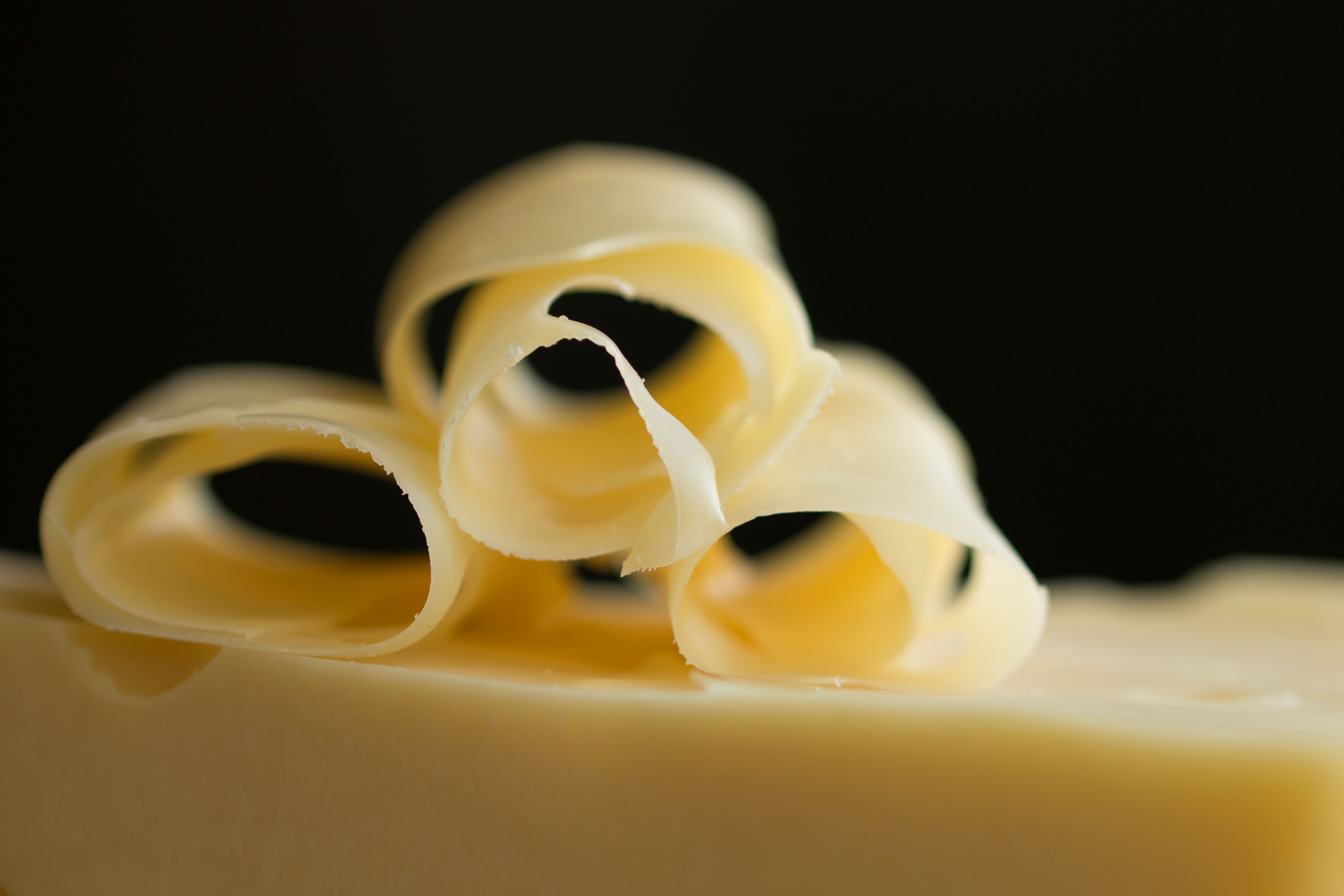 Macro shot of elegant cheese curls on a dark background, showcasing texture and curves.