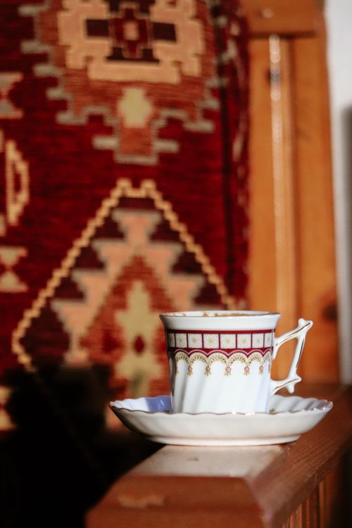 Free An elegant tea cup on a saucer with a traditional geometric patterned background, in warm sunlight. Stock Photo