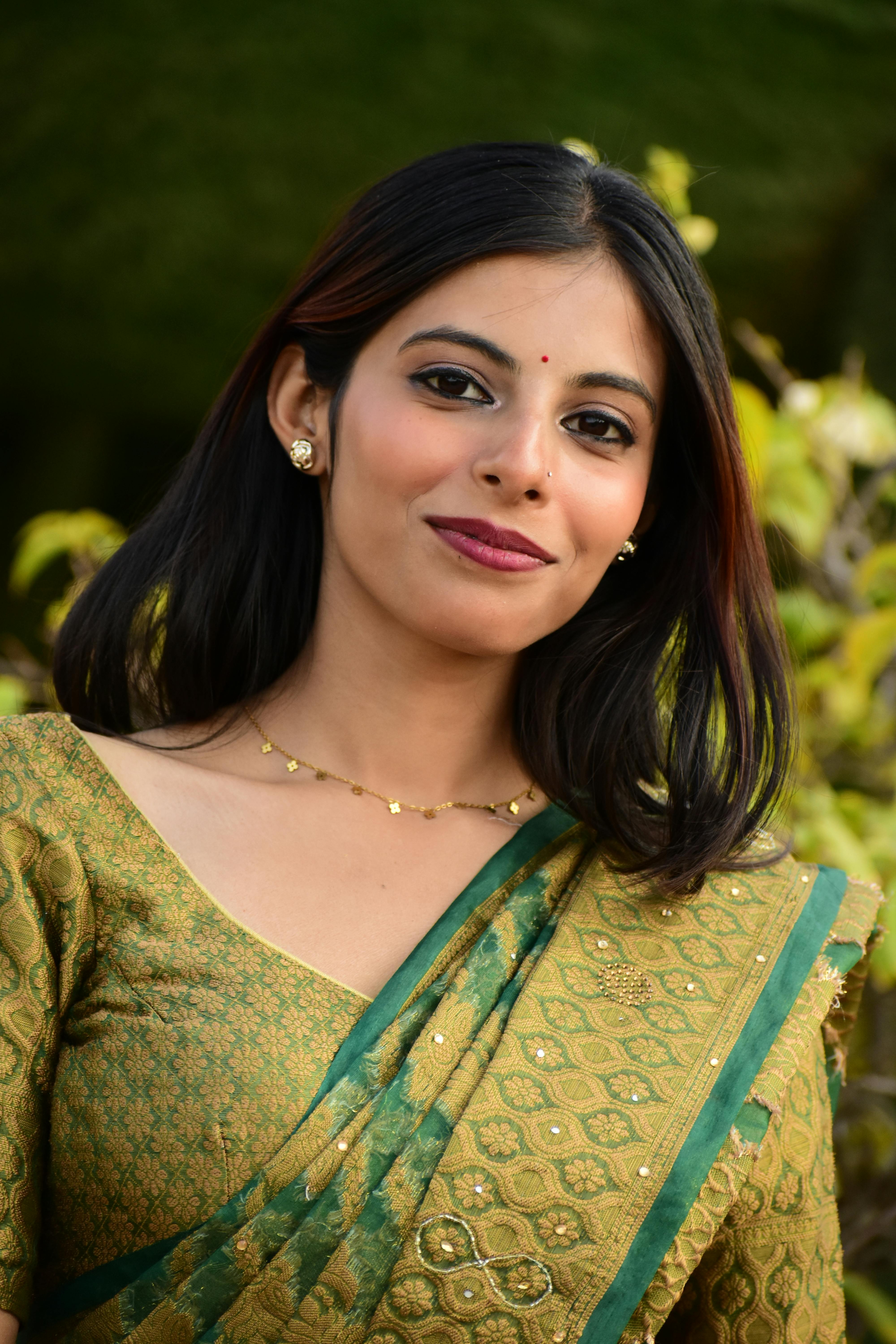 Portrait of a young woman in a green saree with natural backdrop. Traditional elegance outdoors.