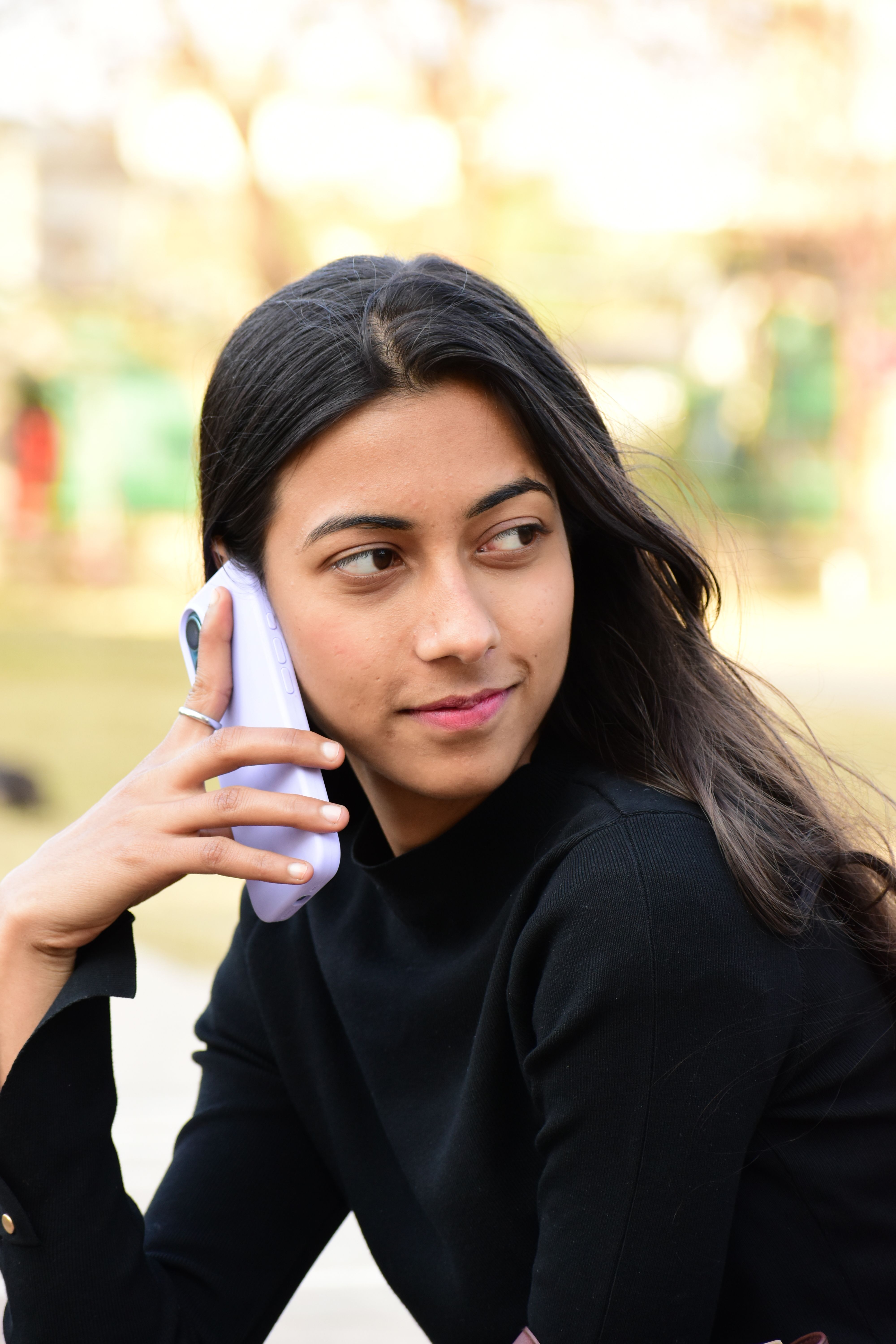 Outdoor portrait of a young woman talking on her phone, exuding style and poise.
