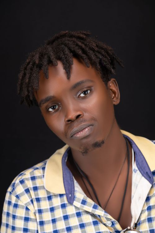 Free Expressive portrait of a young man with dreadlocks wearing a checkered shirt, set against a black backdrop. Stock Photo