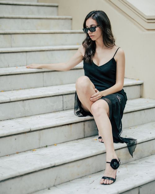 Free Chic woman in sunglasses sitting on stairs in black dress. Urban fashion. Stock Photo
