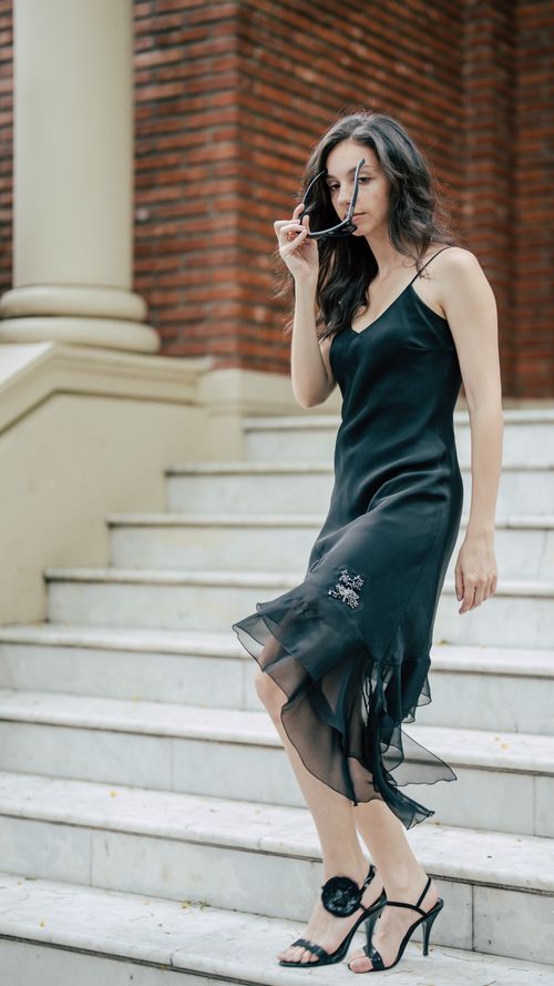 Free Chic woman in a stylish black dress posing on an outdoor staircase. Stock Photo