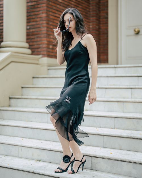 Free Woman in elegant black dress walking down marble steps, exuding confidence and grace. Stock Photo