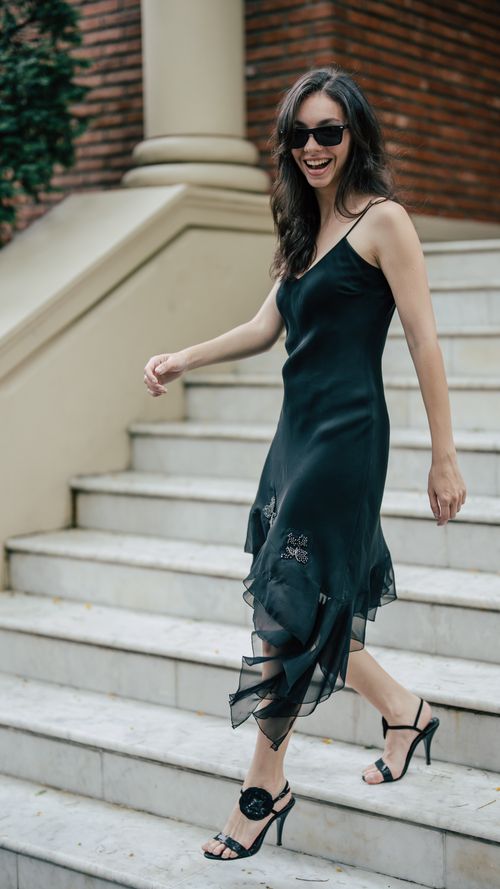 Free Stylish woman in a black dress and heels walking down stairs outdoors. Stock Photo