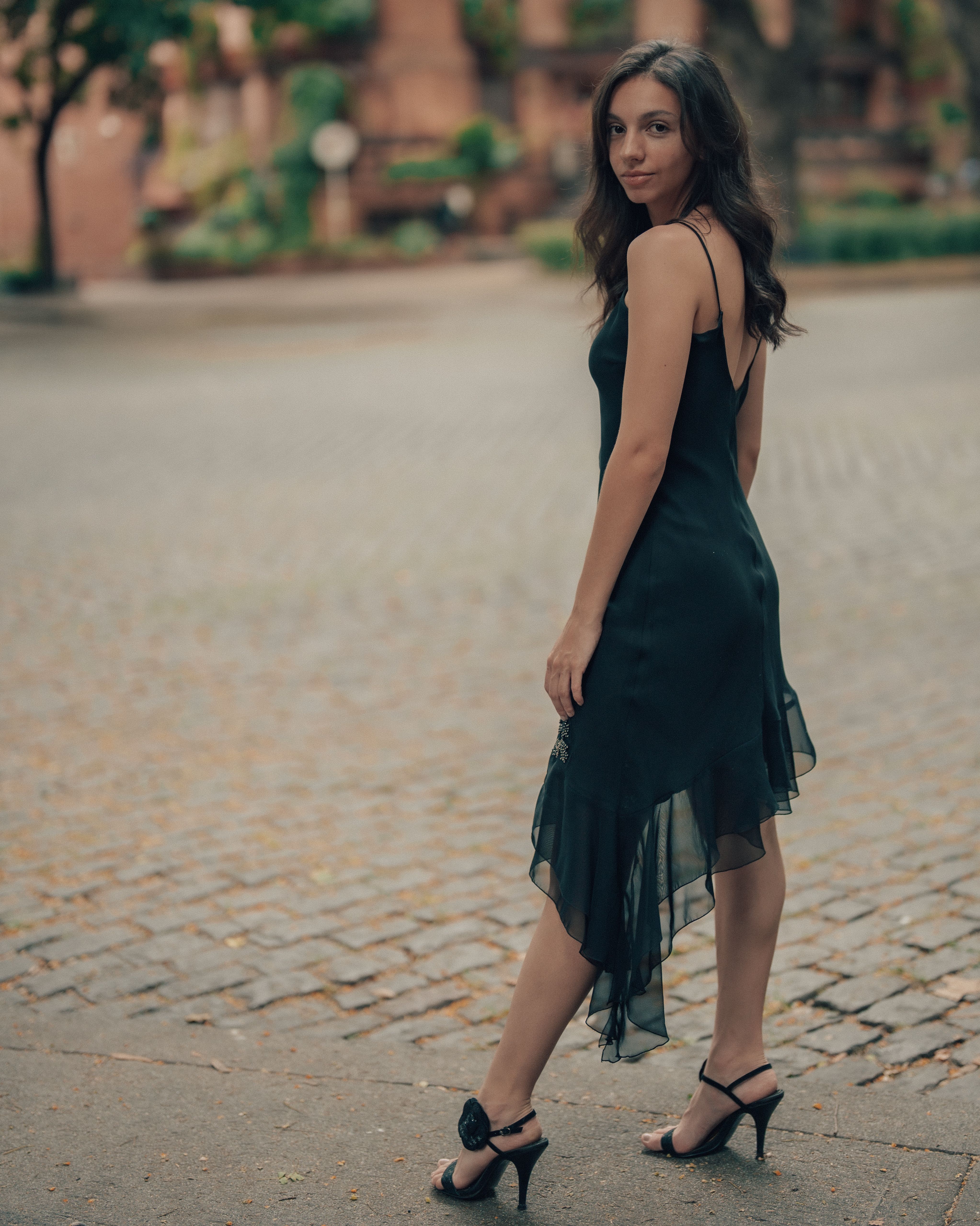 Elegant Woman in Black Dress on Cobblestone Street · Free Stock Photo