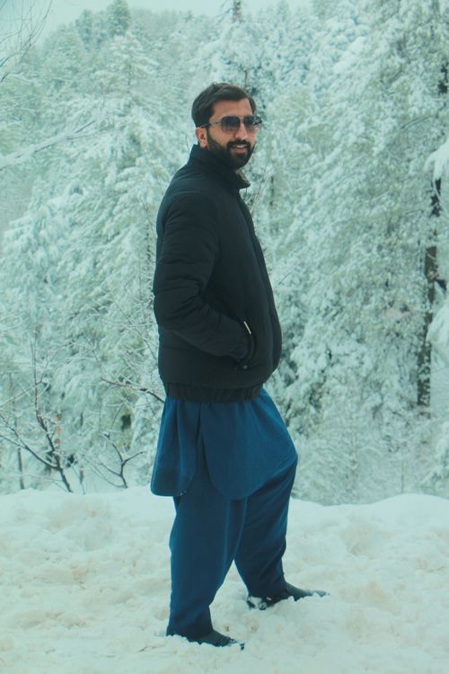 Free A man in a dark jacket and glasses stands in a snowy forest setting, exuding winter style. Stock Photo