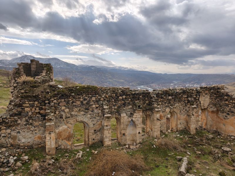 Ancient stone ruins with arches amidst the mountainous landscape of Palu, Elazığ, Türkiye.
