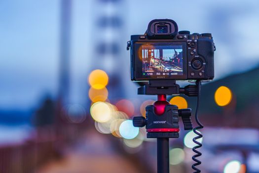 Close-up of a camera photographing the iconic Golden Gate Bridge during twilight.
