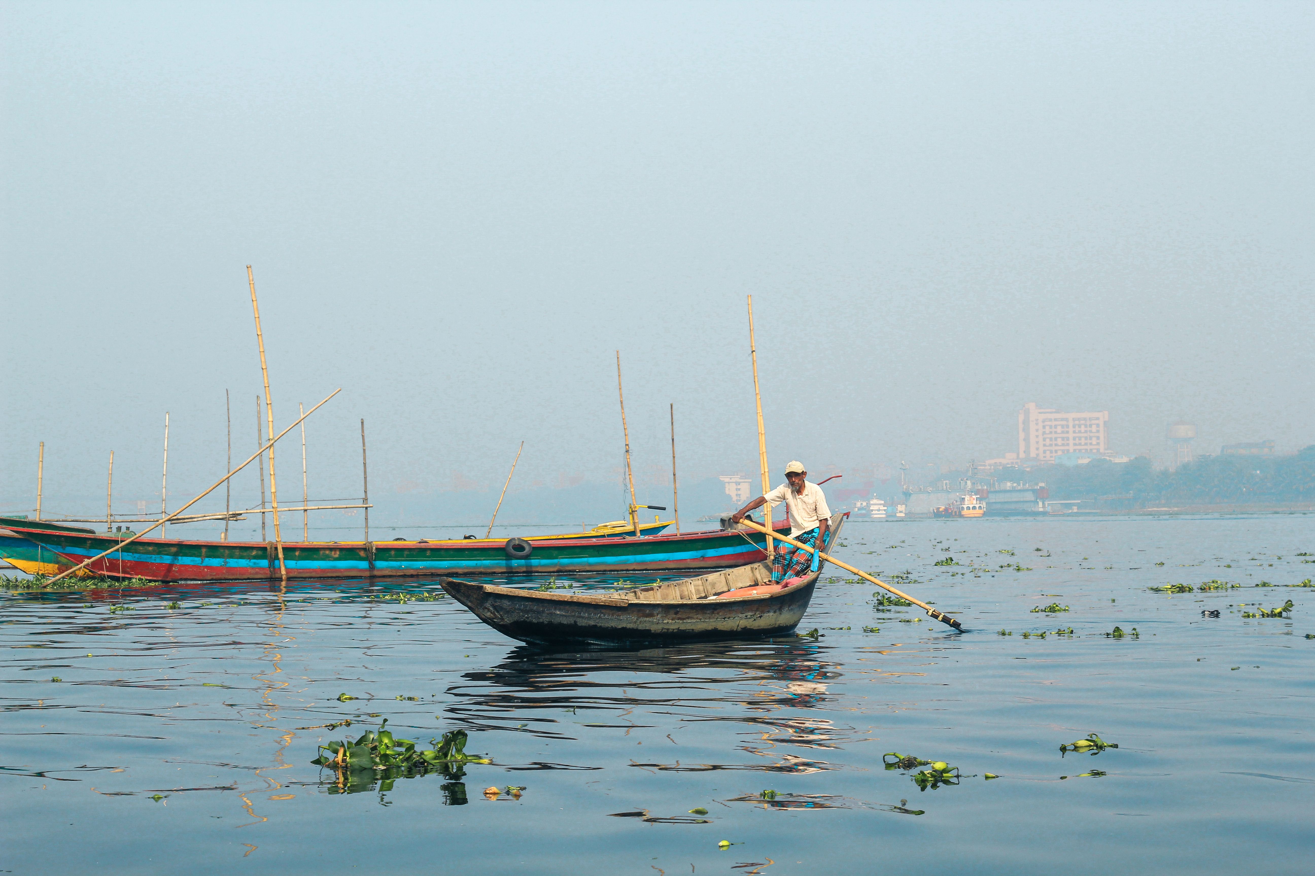A fisherman navigates the bustling waters of Sadarghat, Dhaka, capturing the essence of Bangladesh's traditional river life.
