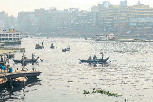 Free Candid shot of traditional boats navigating the Buriganga River in Dhaka, Bangladesh's bustling capital. Stock Photo