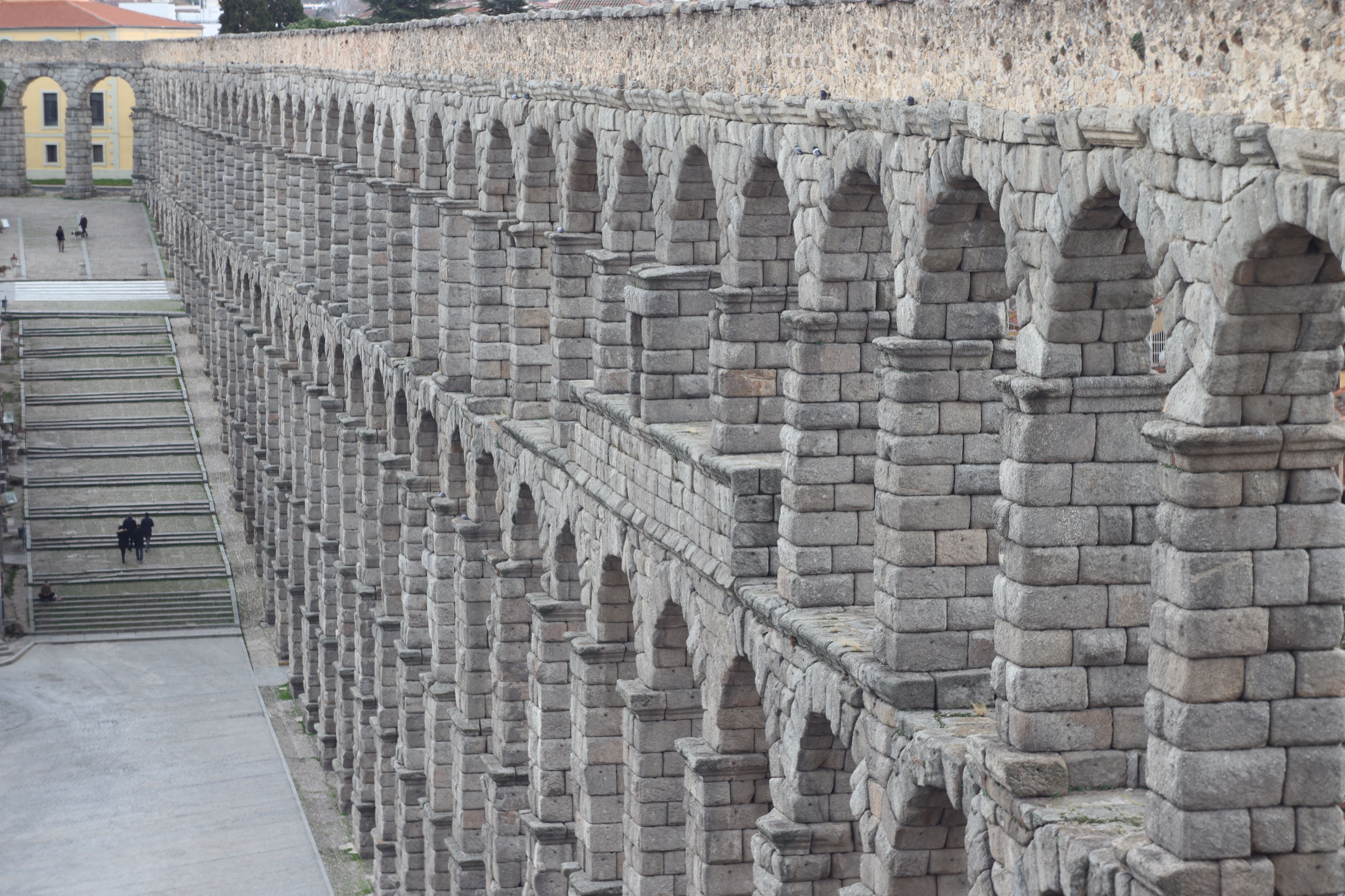 Crowds crossing Plaza del Azoguejo below the Roman aqueduct on a long-weekend afternoon