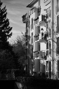 Monochrome image of an apartment building with shadows and trees.