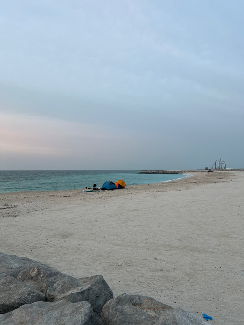 Free Scenic view of beach camping at sunset in Umm Al Quwain, UAE with tents by the shore. Stock Photo