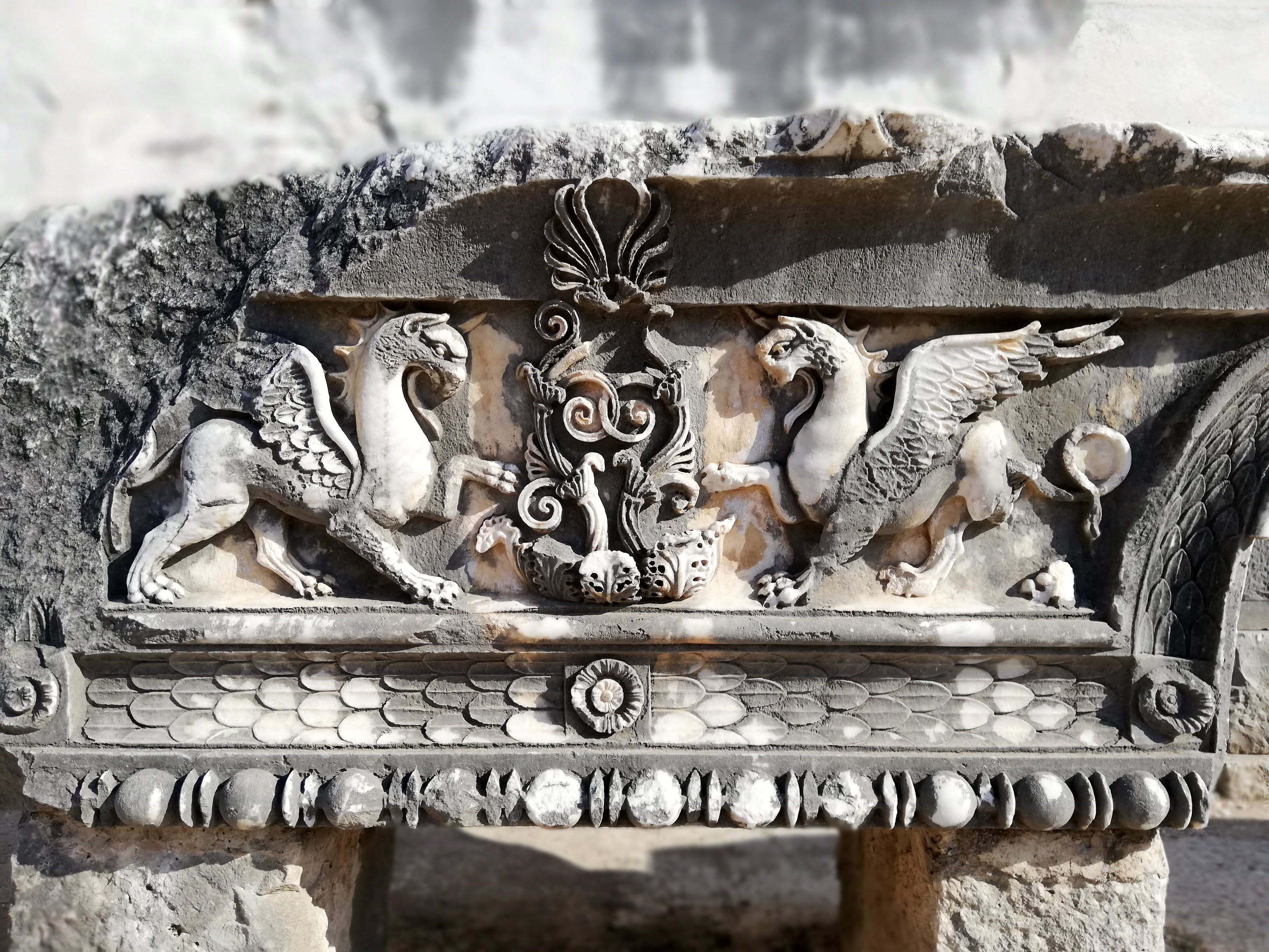 Detailed stone relief featuring griffins and artistic motifs, showcasing ancient craftsmanship.