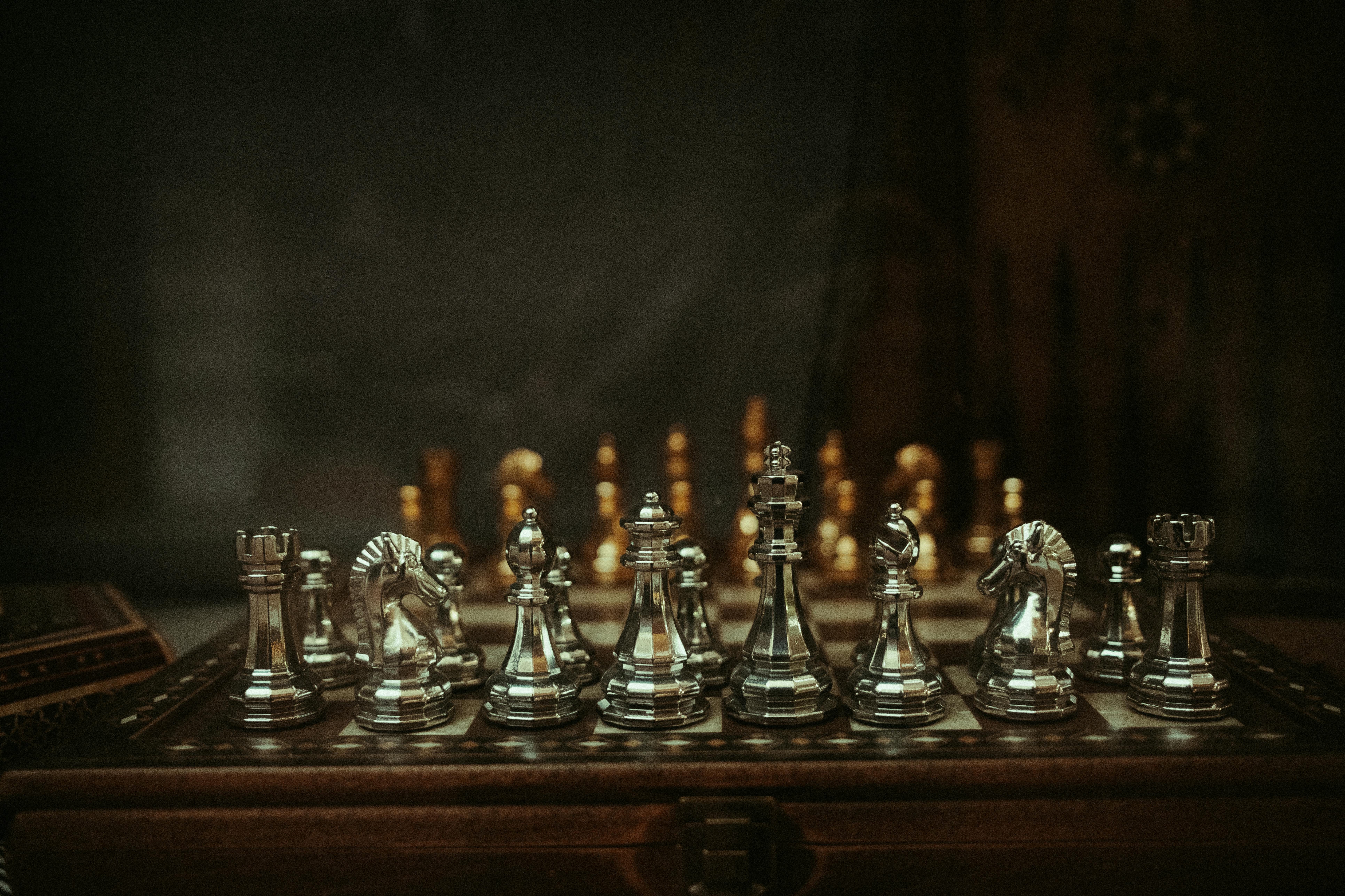 Kostenlos Elegante silberne Schachfiguren auf einem hölzernen Schachbrett in stimmungsvoller Atmosphäre. Stock-Foto