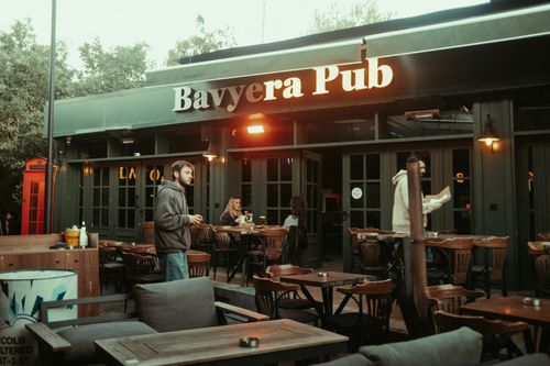 Free Evening outdoor seating at Baviera Pub with patrons enjoying drinks in a relaxed atmosphere. Stock Photo