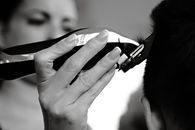 A close-up shot of a person receiving a haircut with electric clippers.