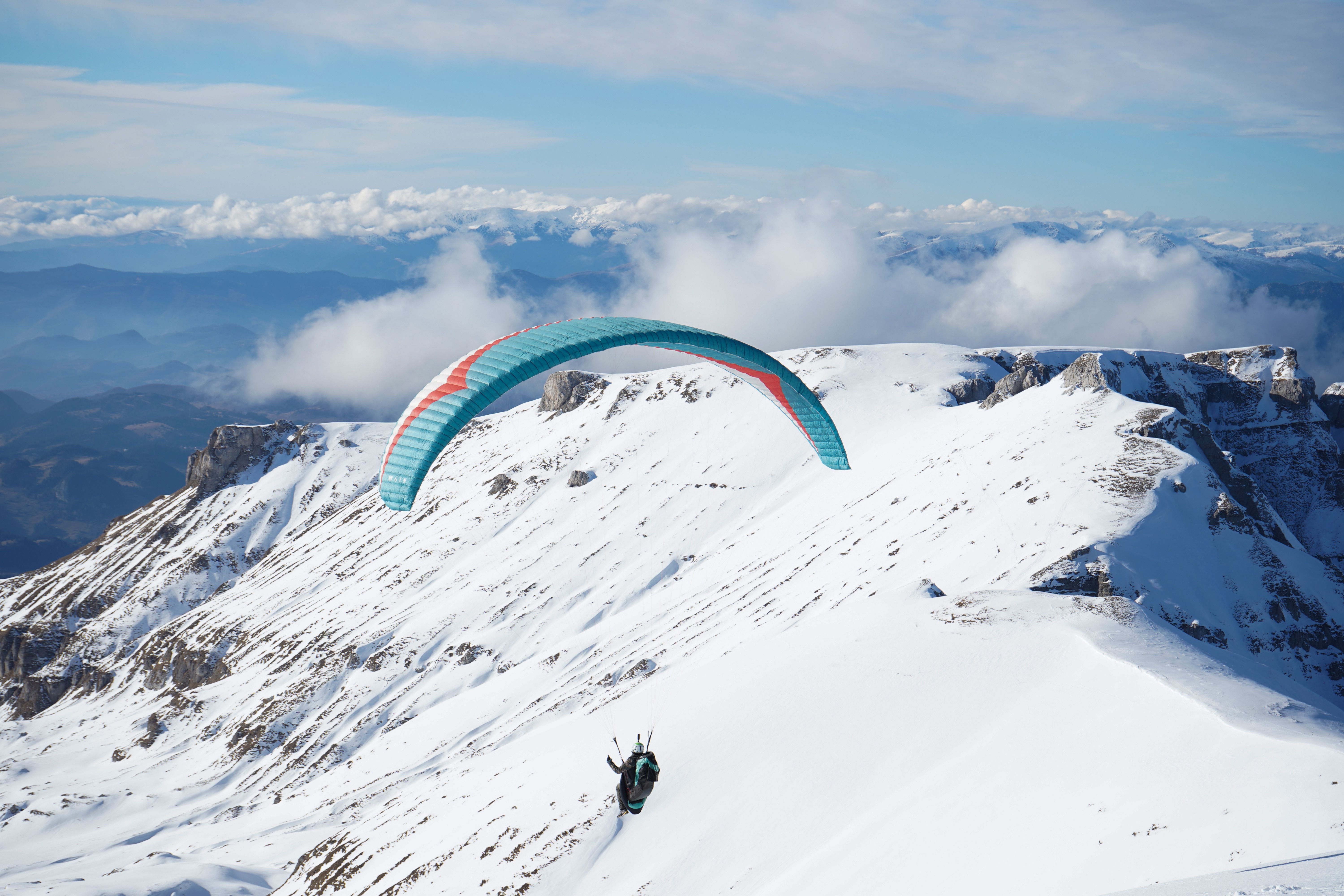 Paraglider Soaring Over Snowy Mountain Peaks