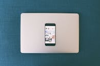 智能手机平放在笔记本电脑上，屏幕上显示着社交媒体照片