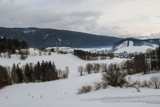 Scenic winter view of snow-covered fields and hills in Autrans-Méaudre-en-Vercors, France.