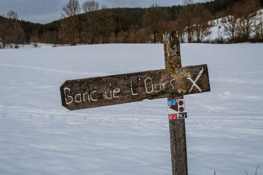Rustic signpost in snowy winter landscape at Autrans-Méaudre-en-Vercors, France.