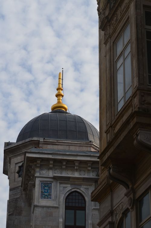 Free A detailed view of a building's dome with a golden finial against a cloudy sky Stock Photo