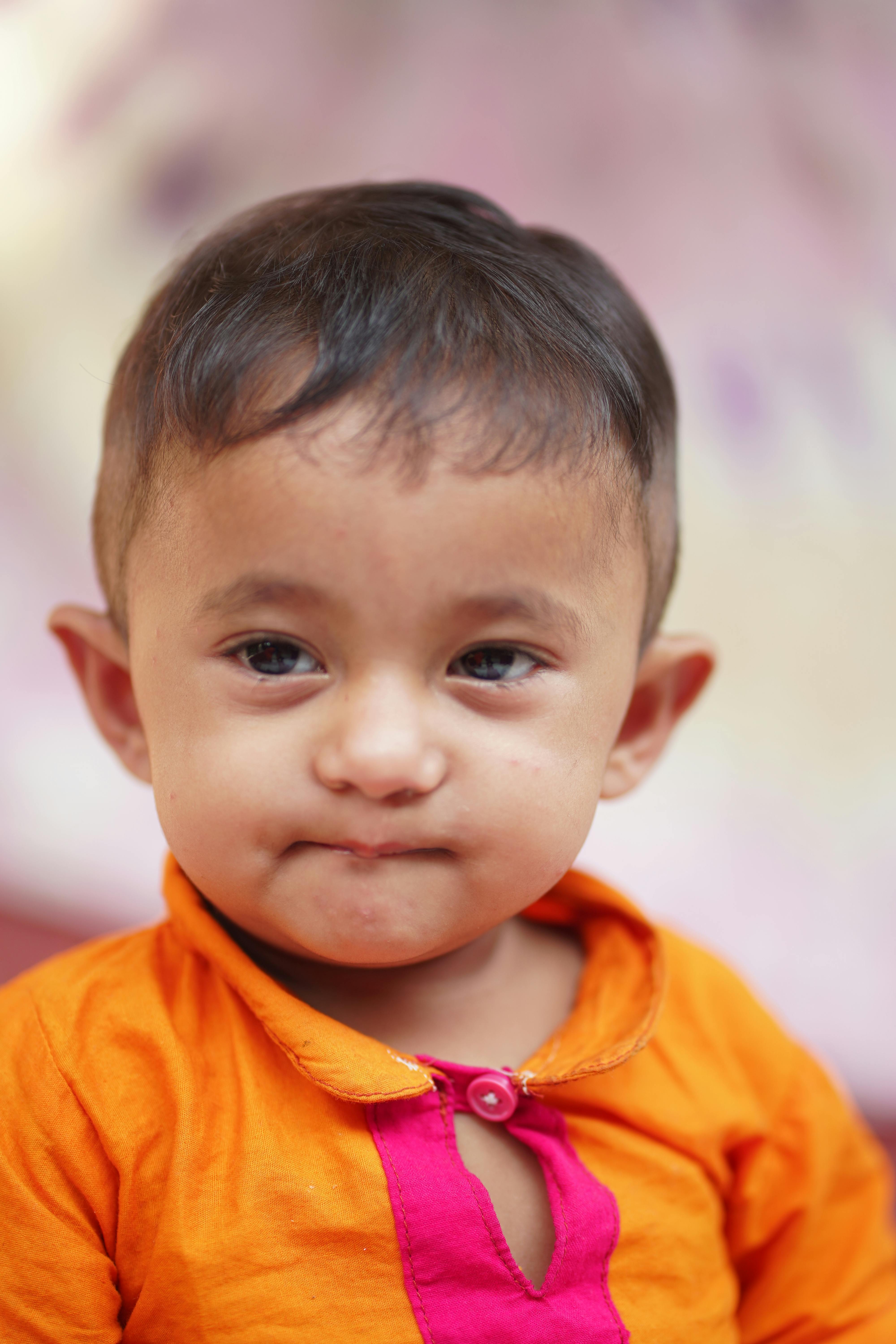 Безкоштовне Крупний план портрета милої дитини в яскраво-помаранчевому вбранні з грайливим виразом обличчя. стокове фото