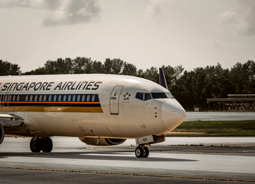 Free Singapore Airlines plane taxiing on airport runway under cloudy skies. Stock Photo
