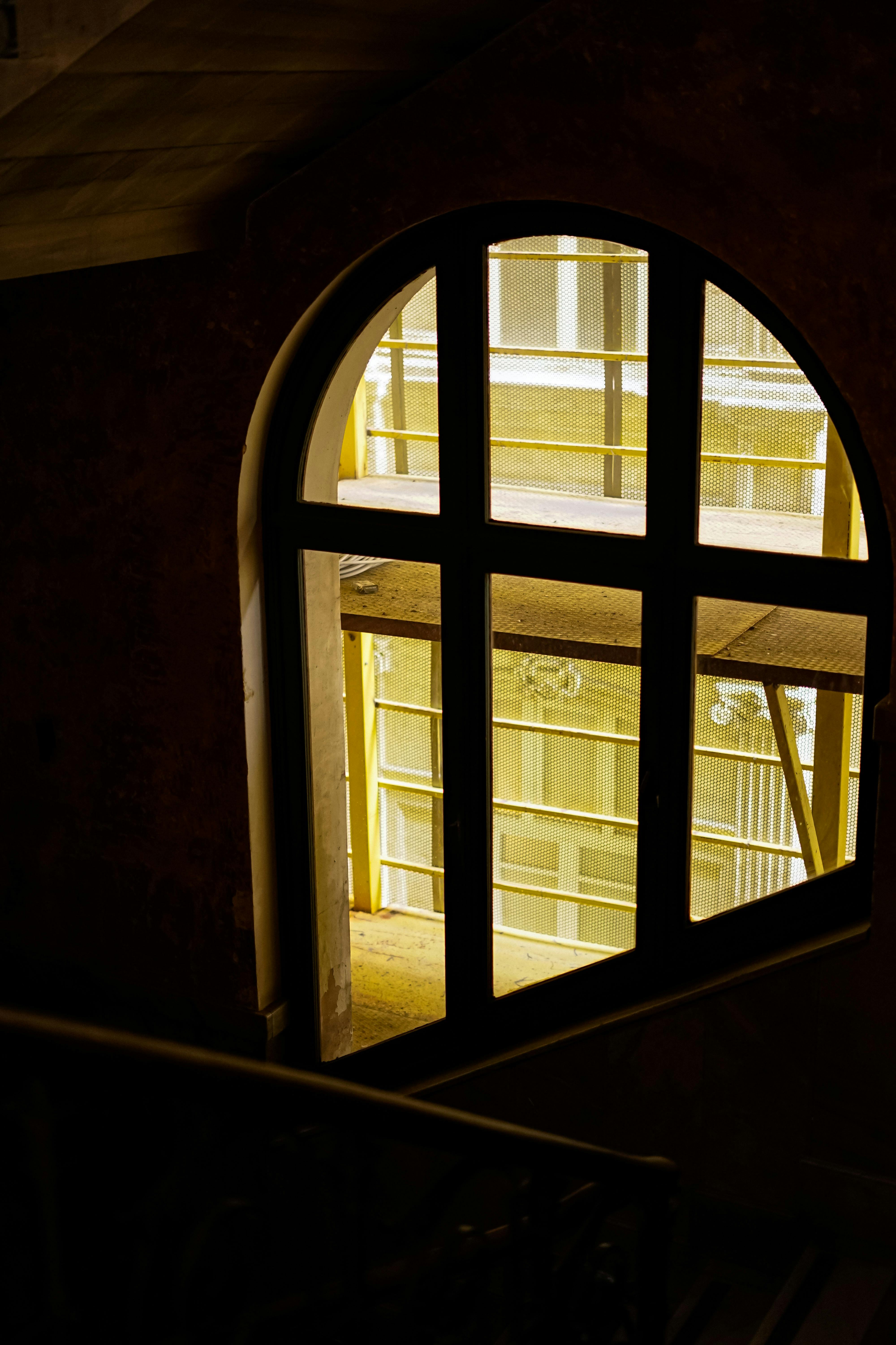 bezplatná Pohled do interiéru klenutým oknem zobrazujícím venku stavební lešení. Základová fotografie