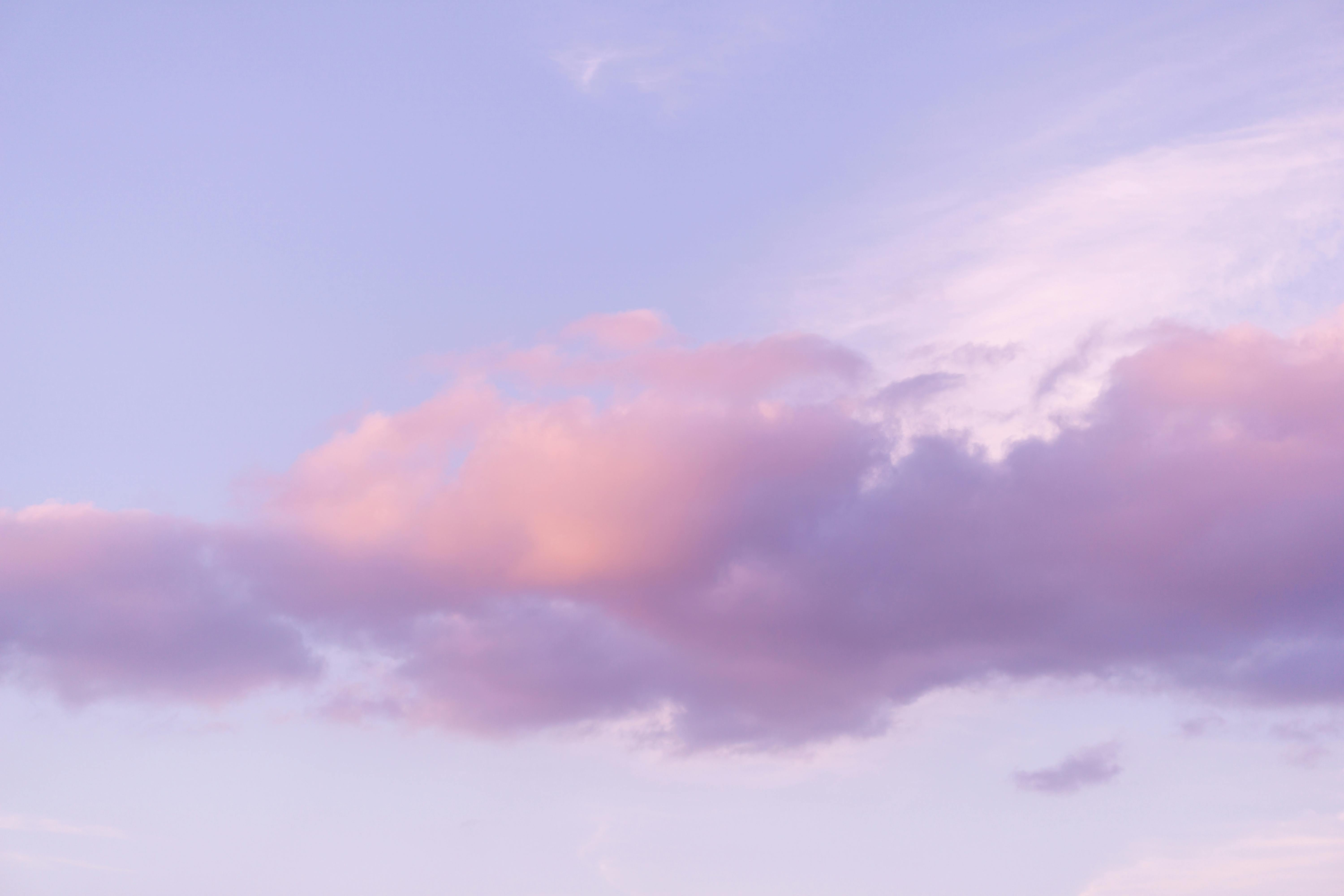 Gratis Et beroligende syn af lyserøde og lilla skyer, der svæver på en klar himmel under solnedgang. Lagerfoto