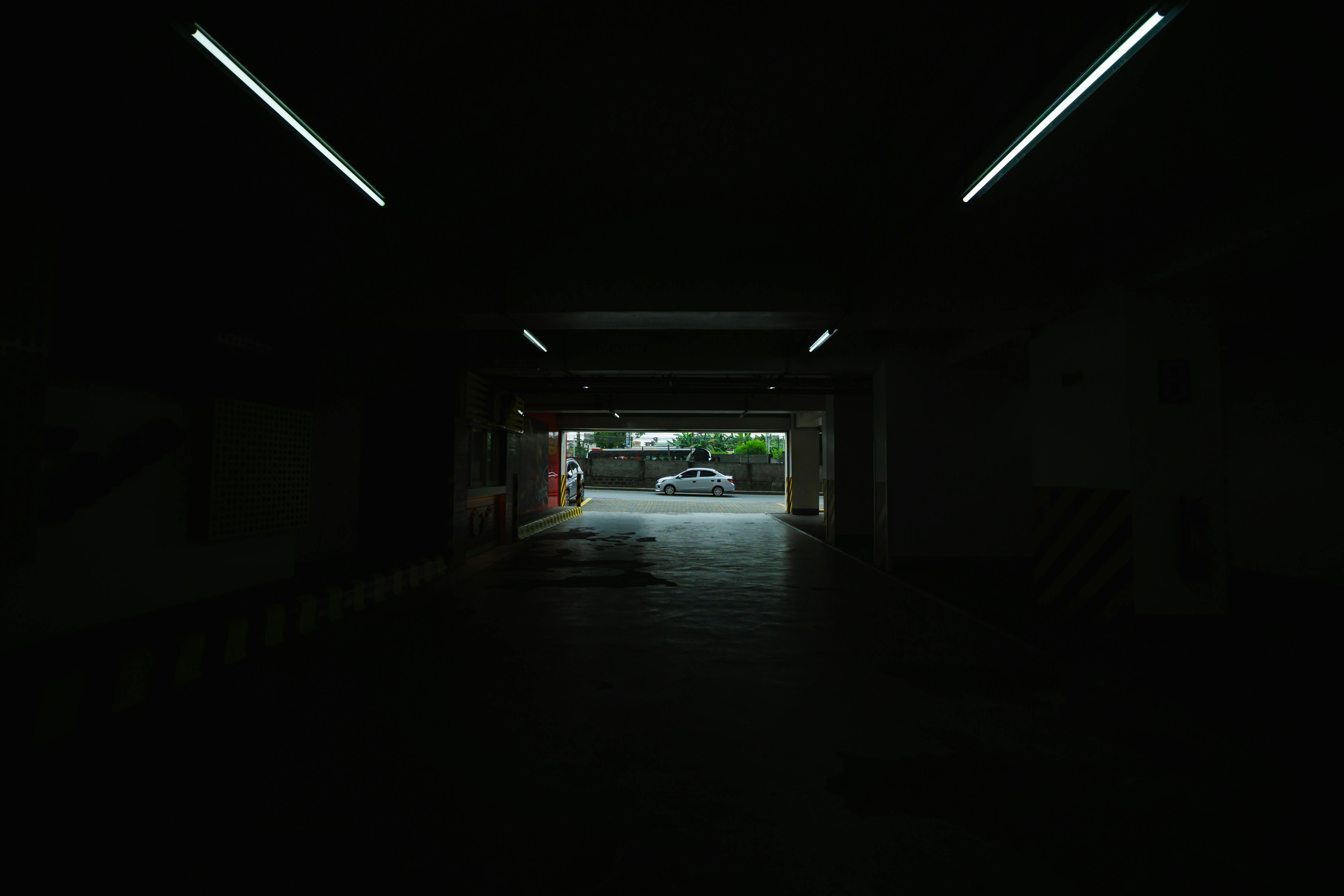 Free A dimly lit underground parking space opening to a bright street view. Stock Photo