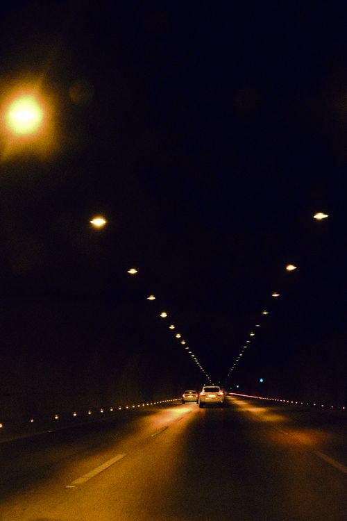 Free A nighttime drive through a lit tunnel with two cars on an empty road, highlighting urban solitude. Stock Photo