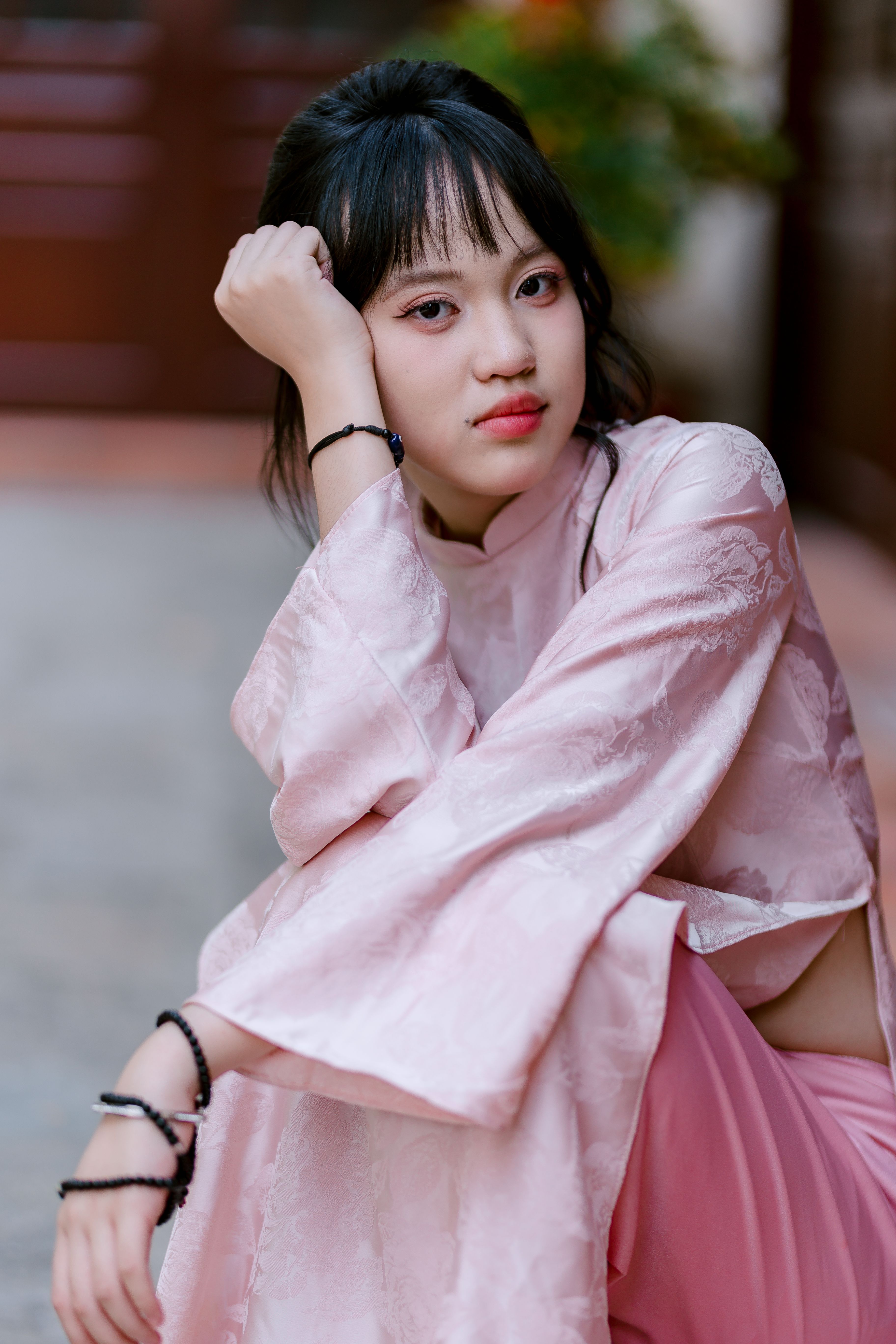 Portrait of a young woman in a pink traditional dress posing indoors with thoughtful expression.