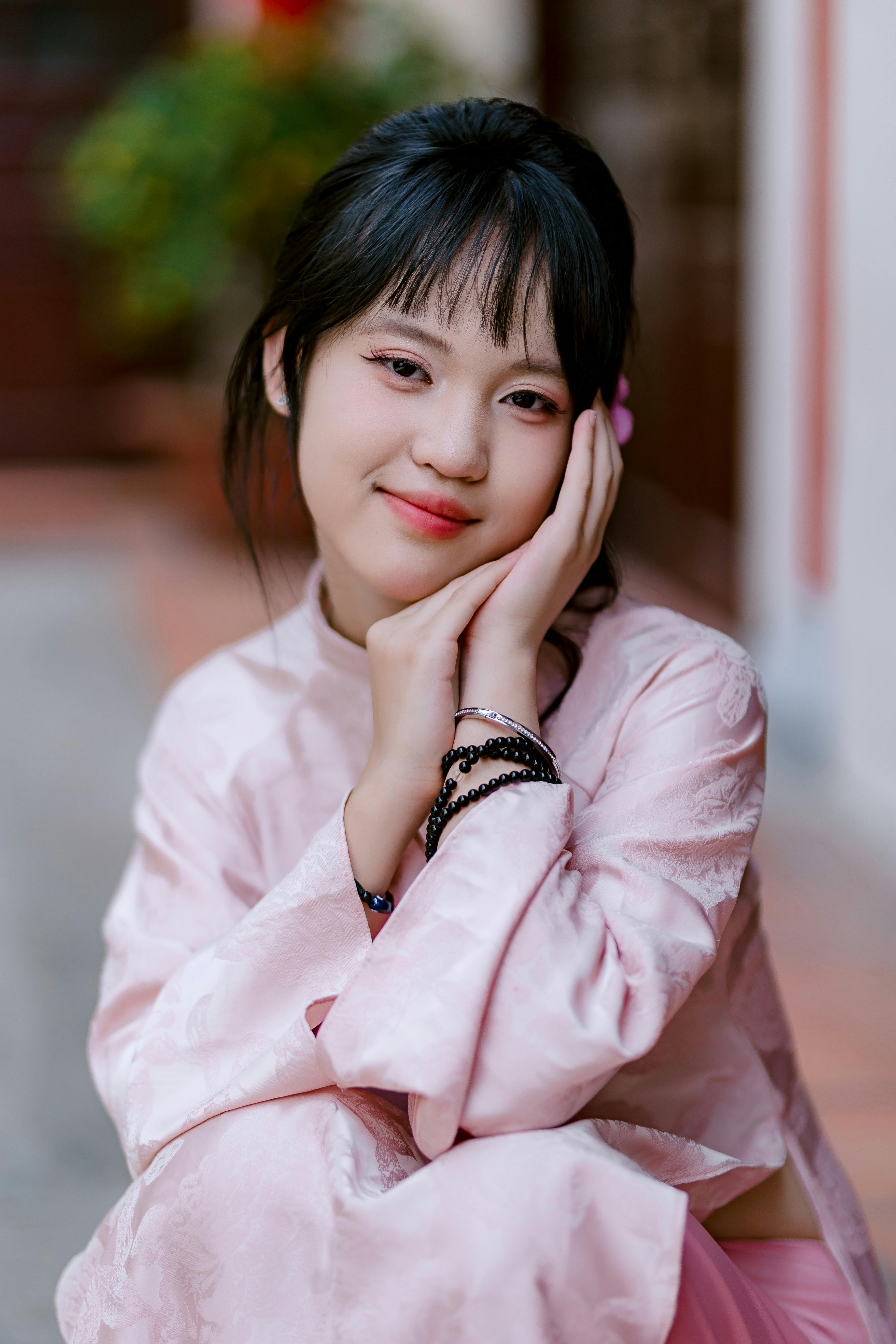 Charming portrait of a young woman in a pink traditional dress, smiling warmly.
