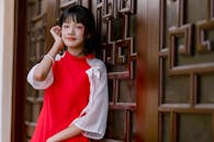 Young Woman in Red Dress Leaning on Wooden Wall