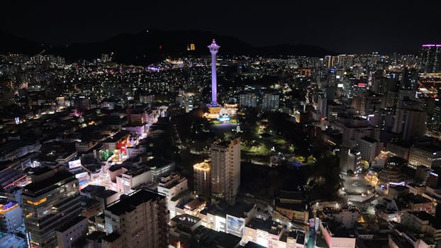 Stunning aerial shot of Busan Tower surrounded by illuminated cityscape at night in Busan, South Korea.