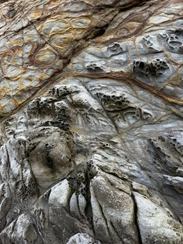 Close-up view of intricate sandstone formations with honeycomb weathering patterns along California's rugged coastline.