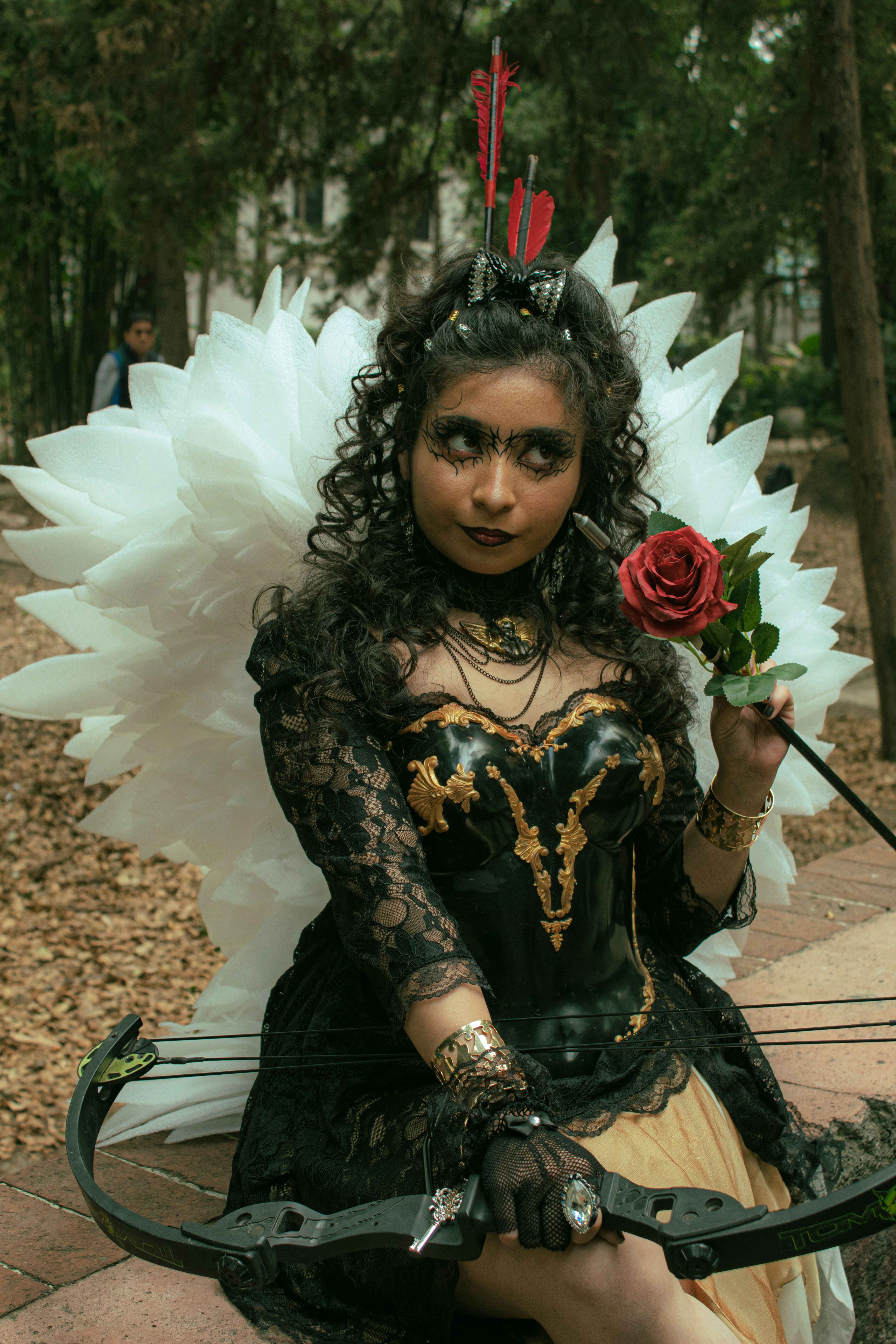 Cosplay Angel with Bow and Rose in Forest Setting · Free Stock Photo