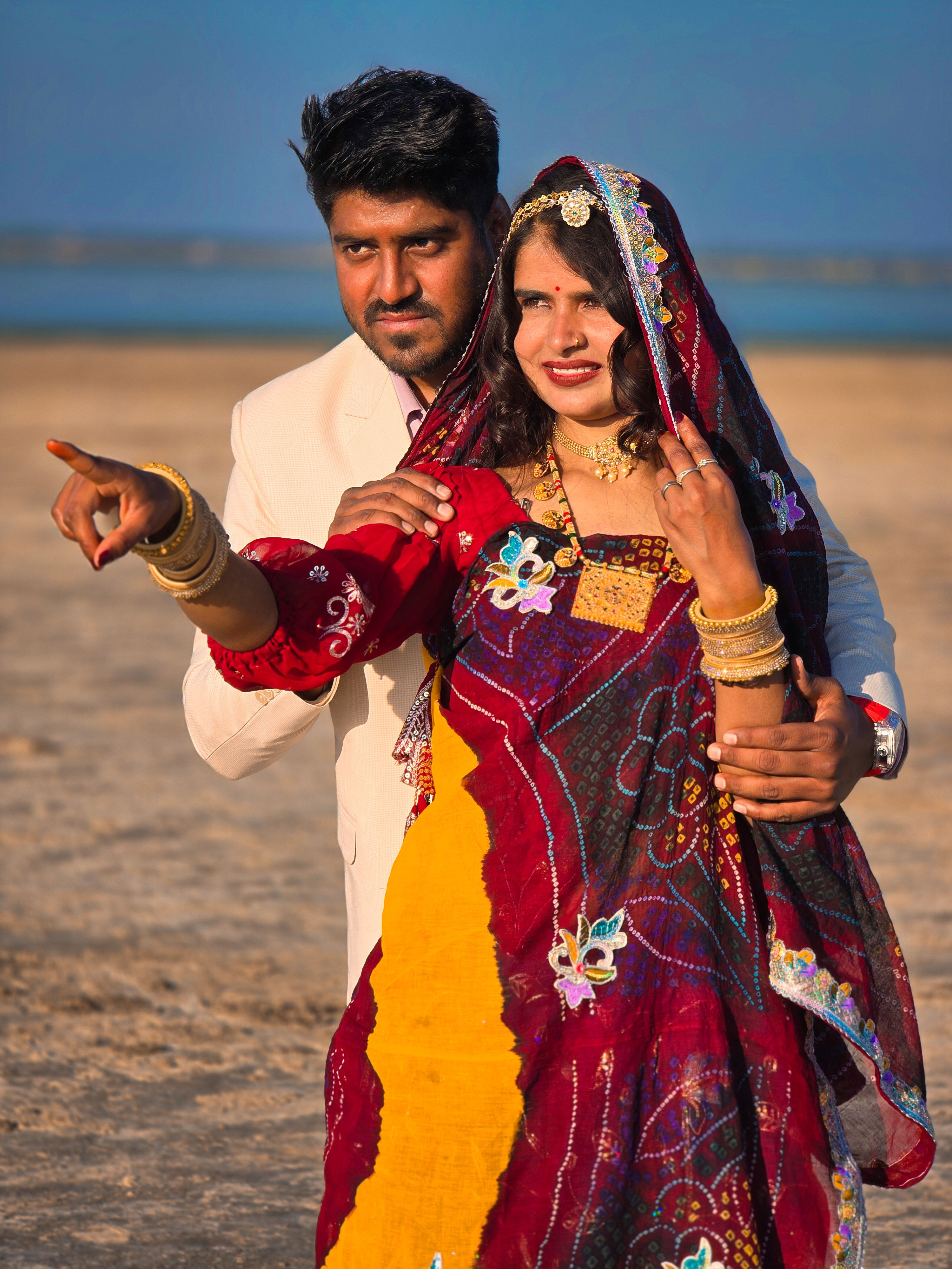 Happy couple in vibrant traditional clothing enjoys a sunny day at the beach.