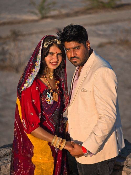 Free Couple in traditional ethnic dress posing outdoors with warm, vivid hues during the day. Stock Photo