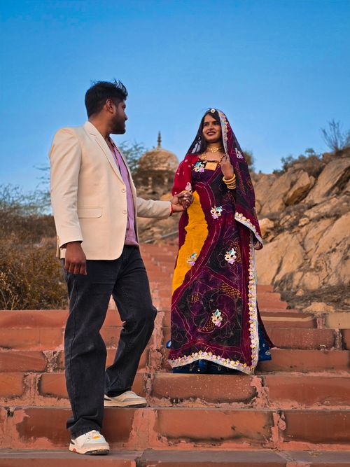 Free A couple in colorful traditional clothing walking down stone steps outdoors. Stock Photo